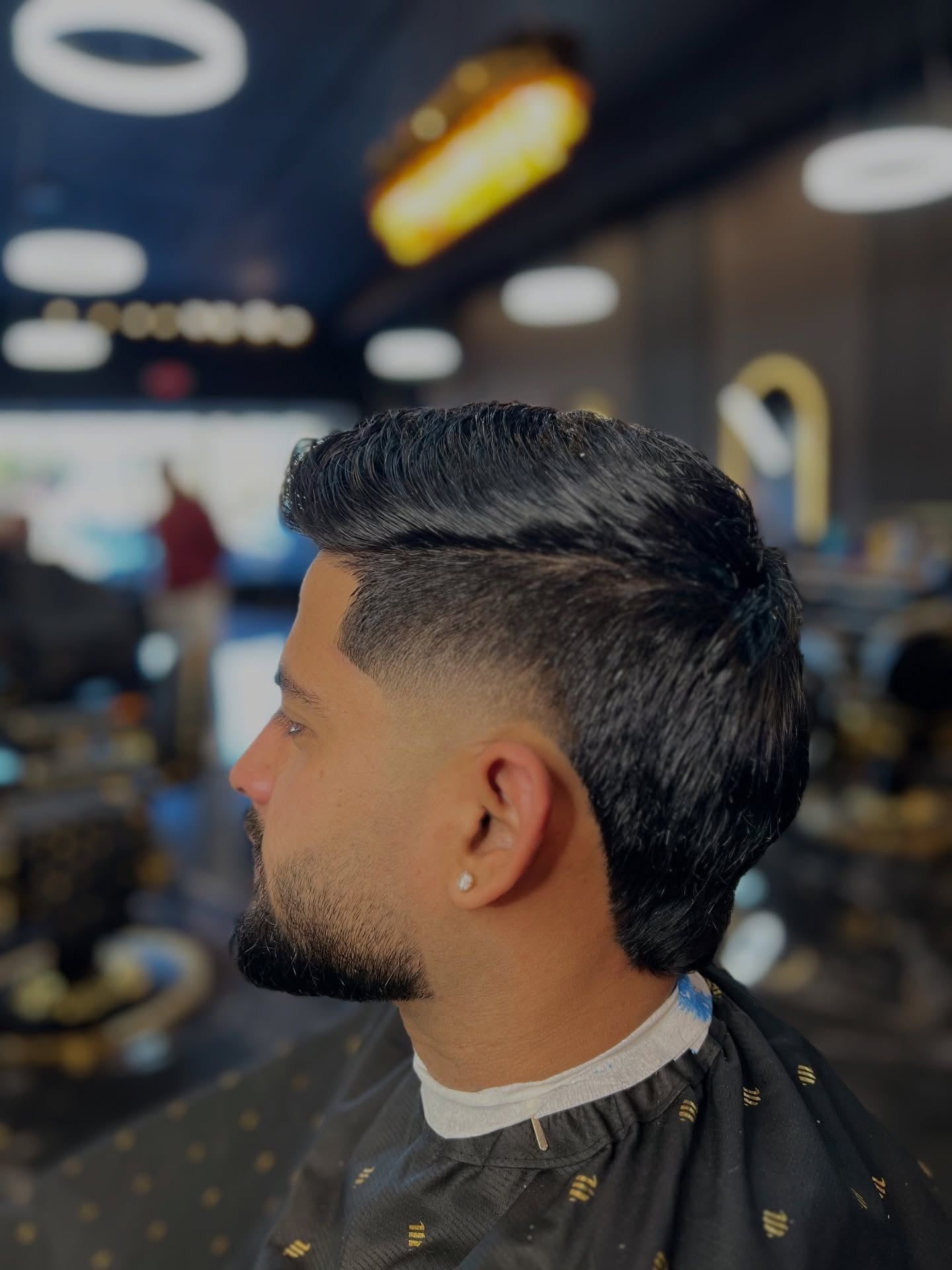 A client in profile with a burst fade around the ear and slicked-back length