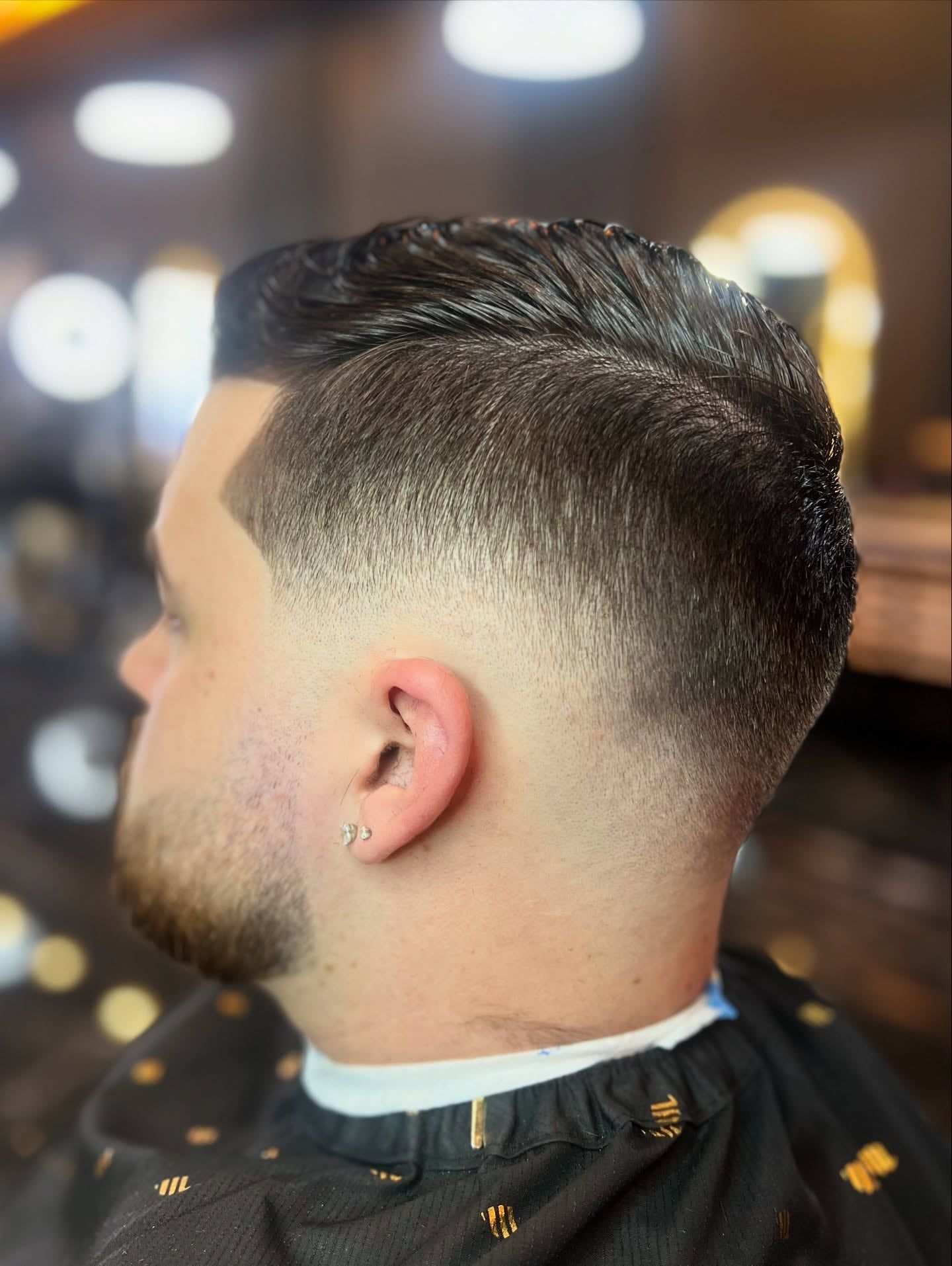 The side and back of a mid fade, blended from skin up into a combed top